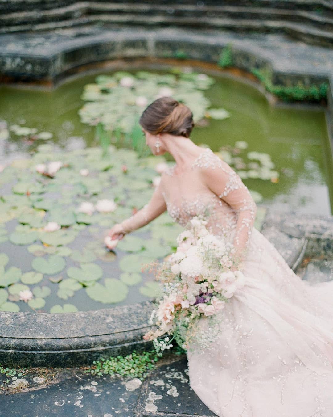 lilly pond bridal portrait with a semi-sheer embellished bridal gown with long sleeves and a garden bouquet