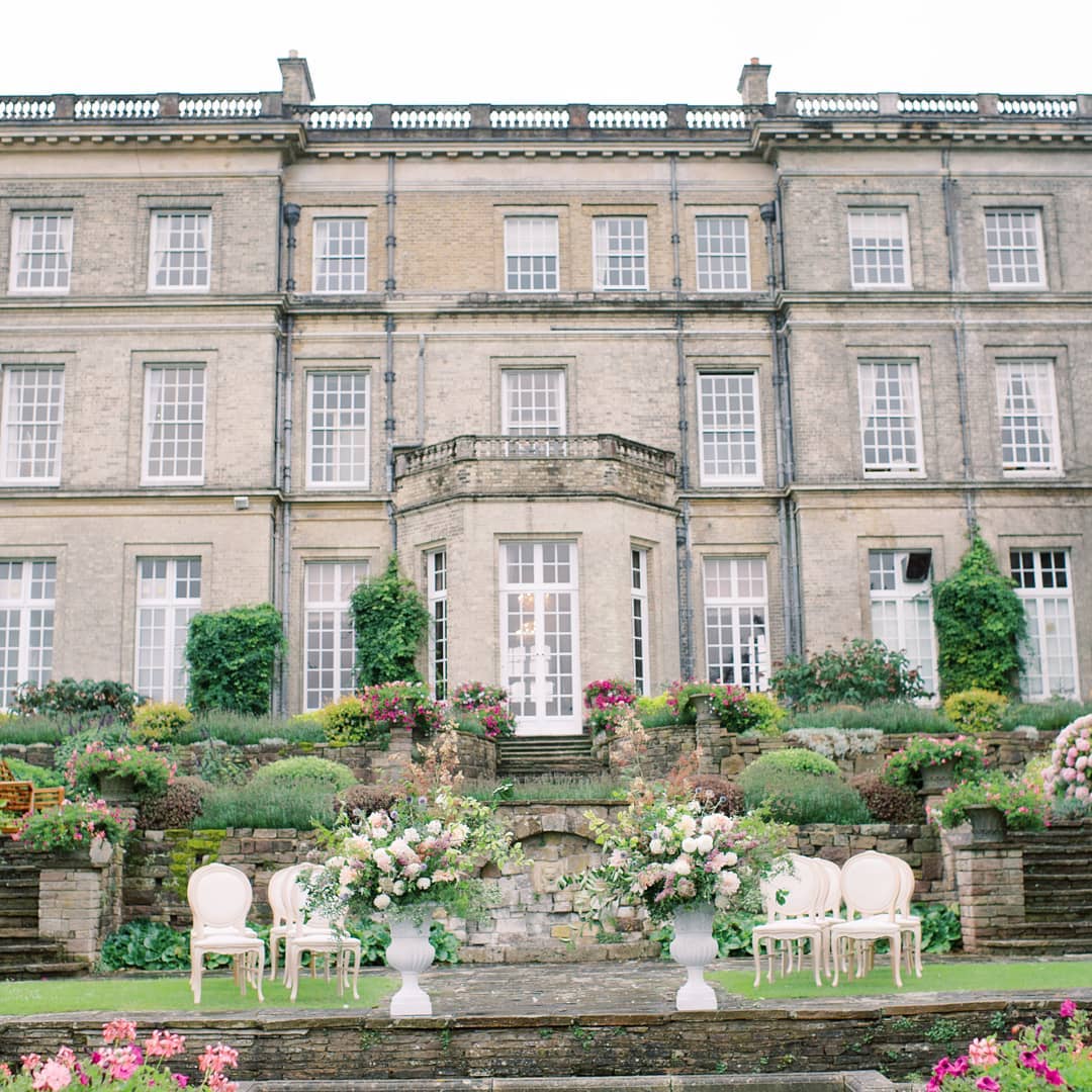 English manor house wedding ceremony in a sunken garden with oversized floral urns