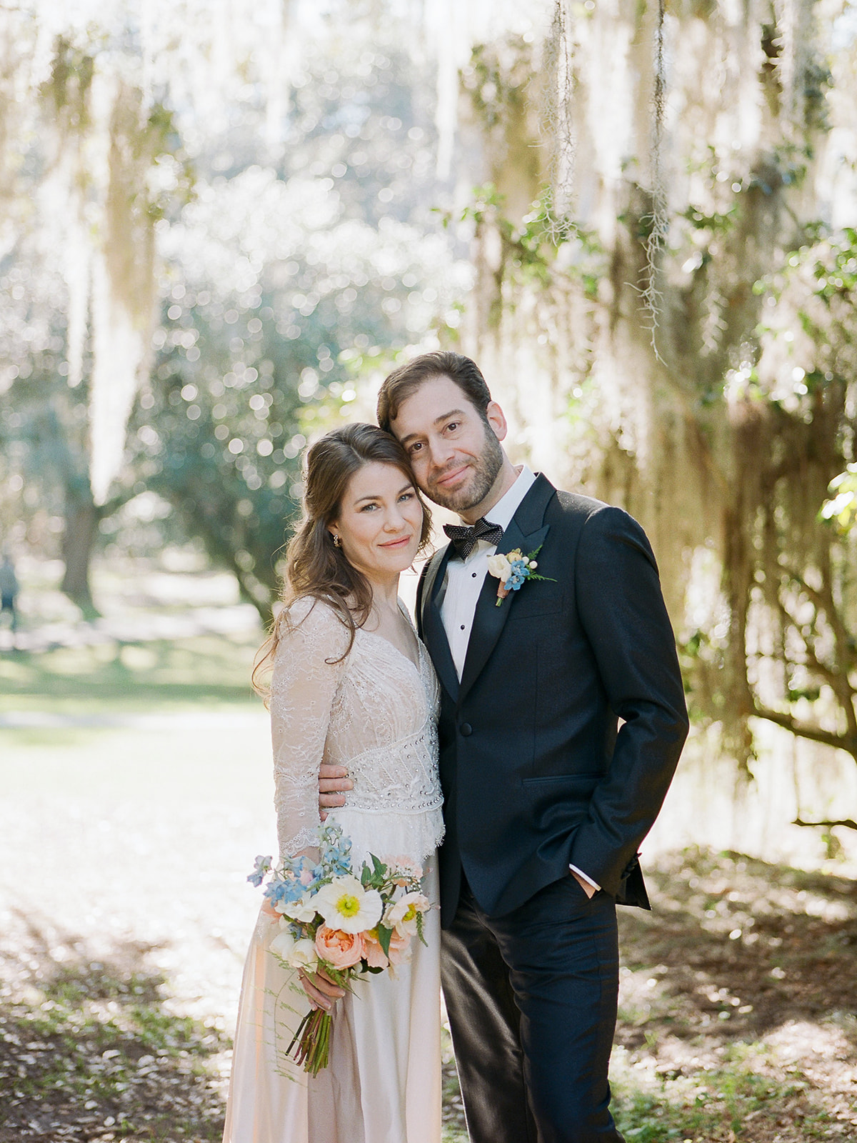 Charleston microwedding with a bride in a long-sleeve lace and beaded wedding dress inspired by a vintage silhouette holding an Icelandic poppy bouquet with roses and sweet pea; planning and design by Willow and Oak Events with photography by Kylee Yee