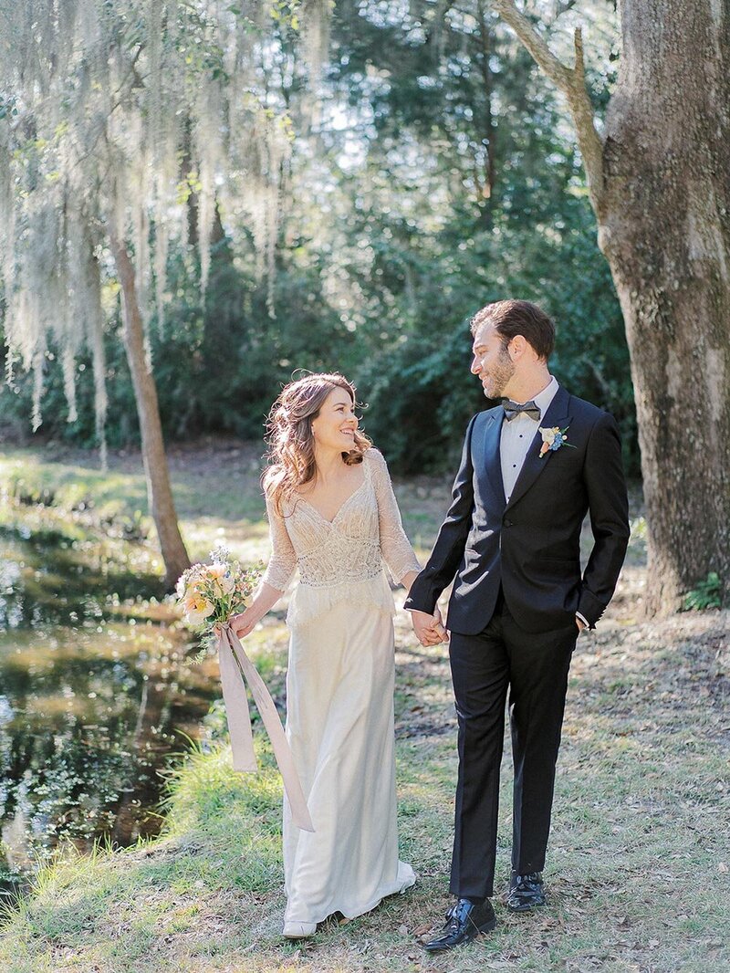 Spanish moss couple portraits in Charleston at Legare Waring House with bride in a lace long-sleeve vintage inspired wedding dress and groom in a black tux, styling by Willow and Oak Events and photography by Kylee Yee