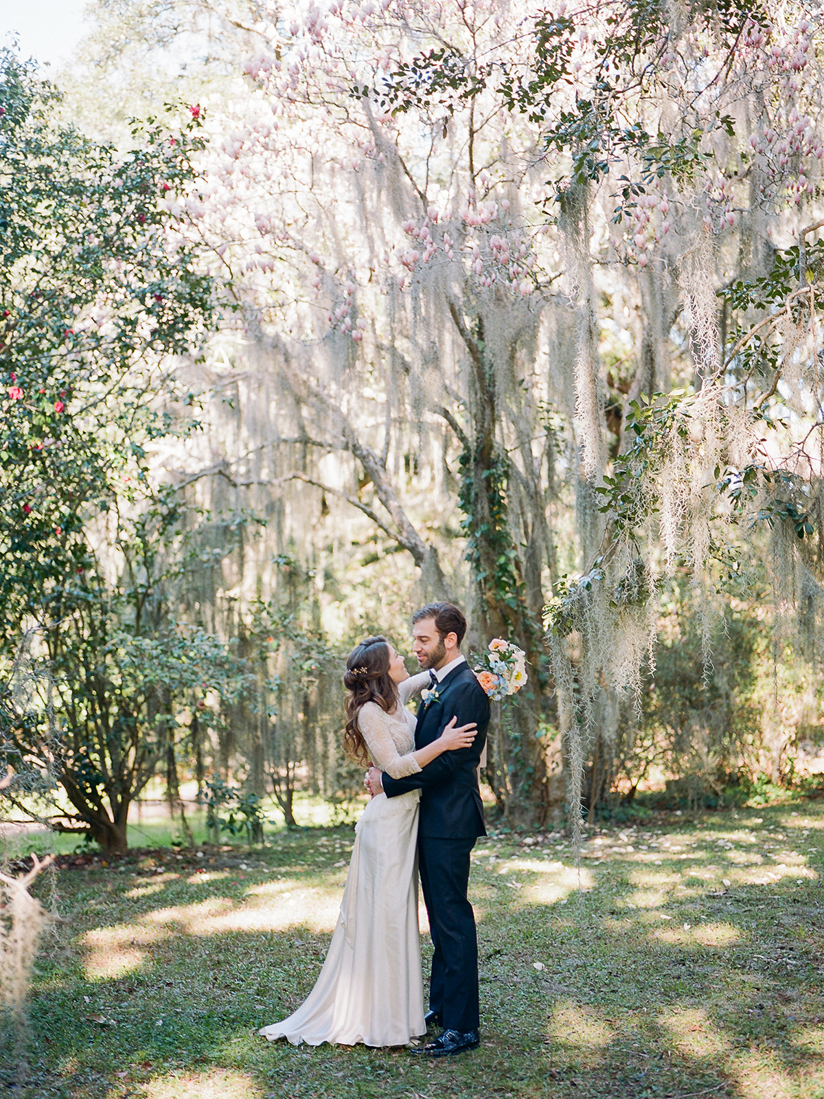 Spanish moss couple portraits in Charleston at Legare Waring House with bride in a lace long-sleeve vintage inspired wedding dress and groom in a black tux, styling by Willow and Oak Events and photography by Kylee Yee