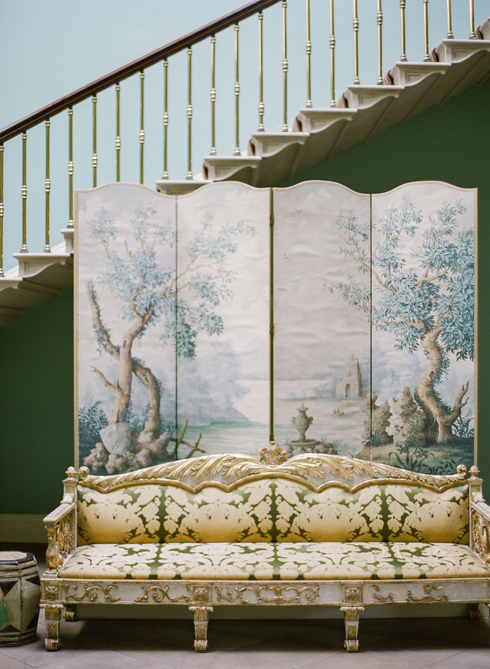 Antique patterned sofa with a handpainted mural room divider backdrop in the stairwell of Ballyfin in Ireland