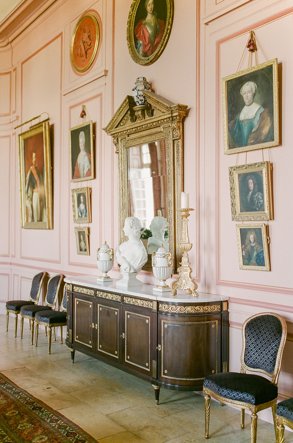 The pink dining room of Chateau du Grand Luce with gallery style portraits
