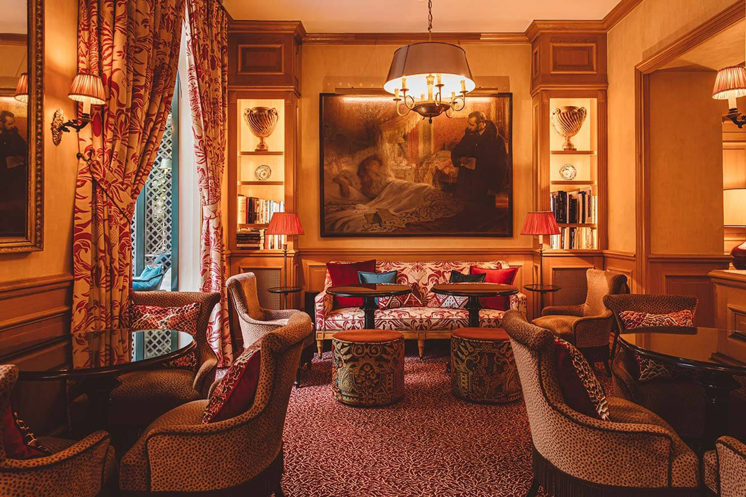 The maximalist red and beige interiors of the Hôtel de l'Abbaye Lounge with petite tables and soft furniture groupings