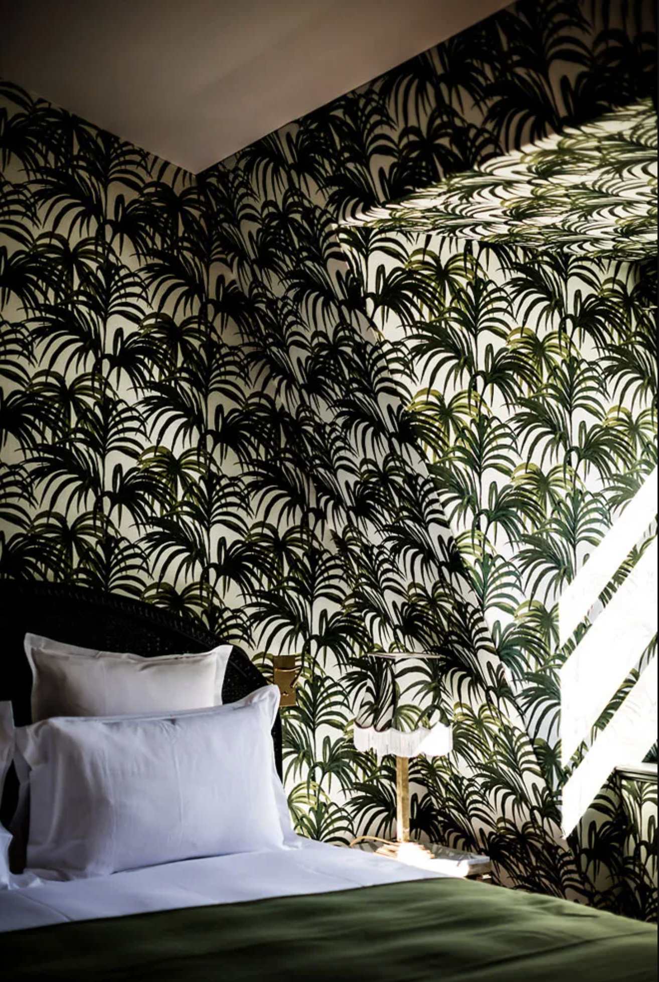 A tropical green palm tree wallpaper suite at Hotel Providence with natural light flooding in from the bedside window