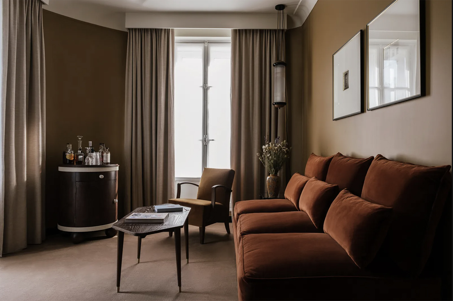 Refined masculine interiors of Hotel Rochechouart in Paris with an amber velvet sofa, a marigold velvet armchair and a mahogany coffee table
