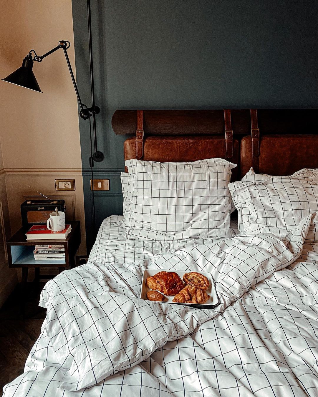 Modern grid-patterned linens and a leather headboard in one of the guestrooms at The Hoxton Paris