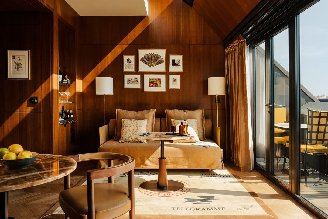 Wood-paneled walls, cafe au lait linen seating, brown marble tables and a scenic balcony in one of the suites at Madame Rêve
