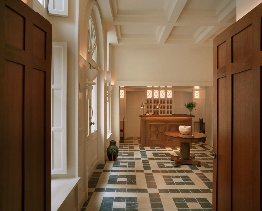 The patterned tile lobby of Chateau Voltaire with a hand-carved wooden check-in desk