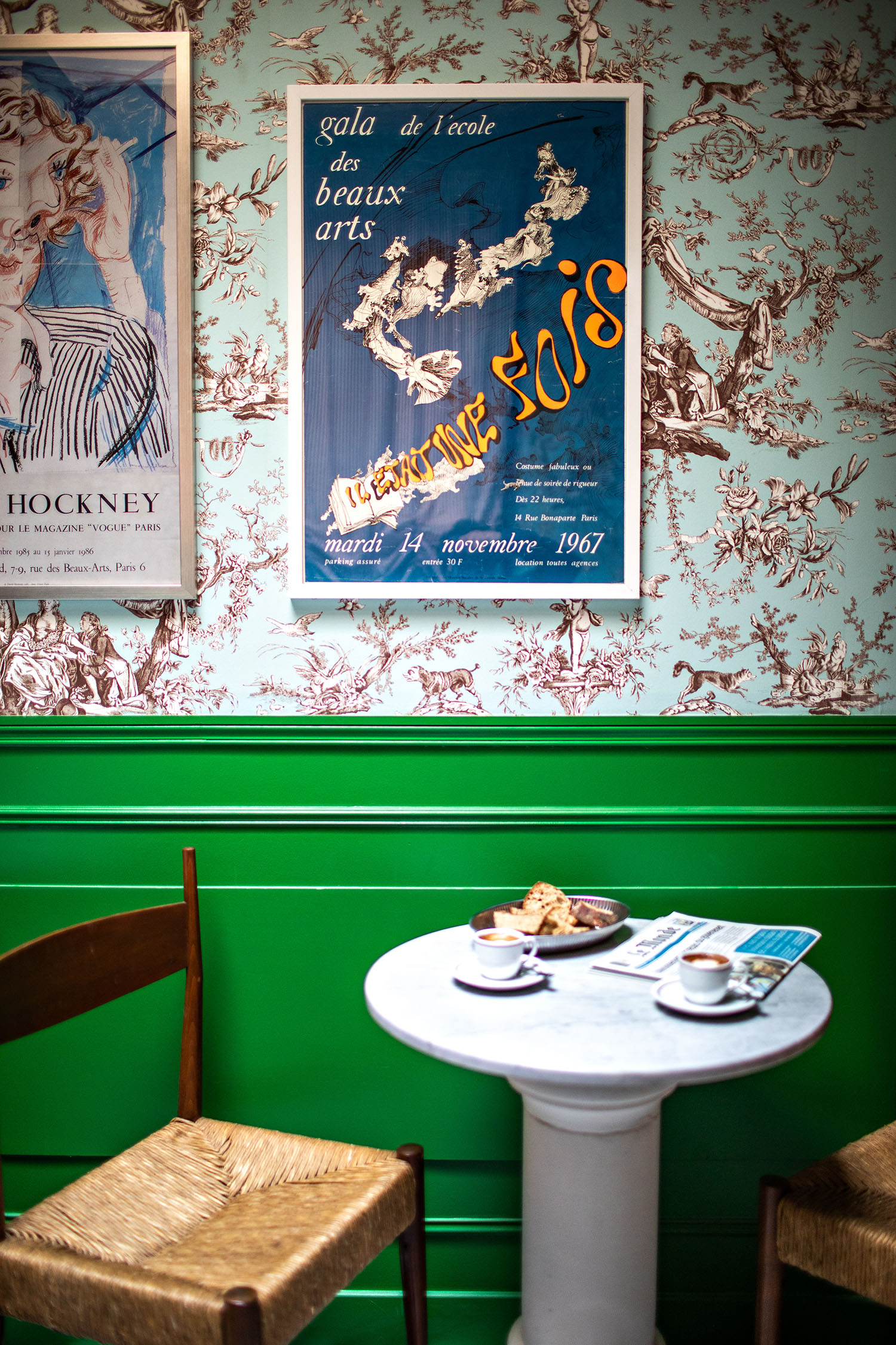 The maximalist breakfast room at Hotel les Deux Gares with blue + brown toile de juoy walls accented with bright green wainscoting and hand-illustrated posters from the 1960's
