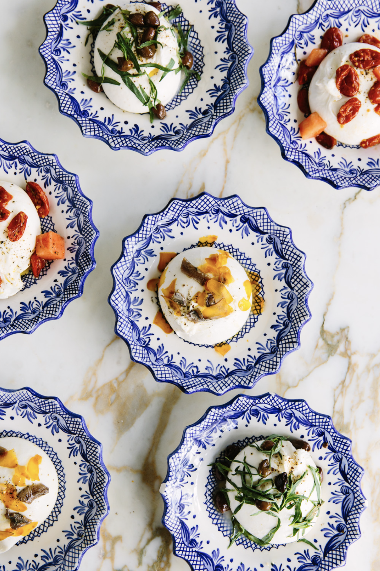 A variety of burrata scoops served on hand-painted blue and white ceramic plates at Pink Mamma