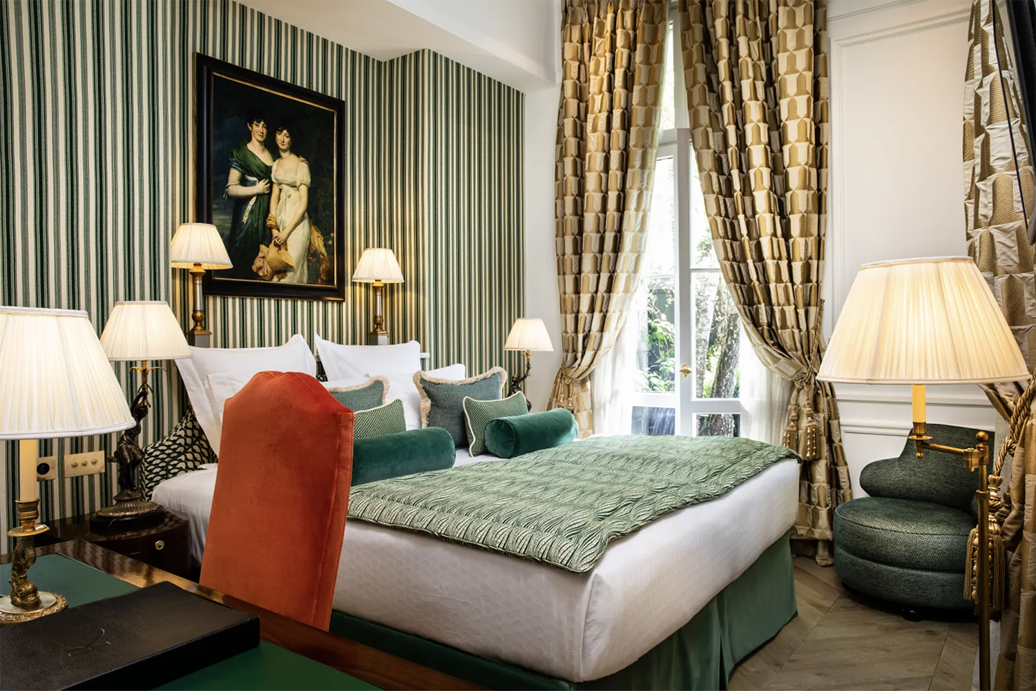 Jewel-toned greens make up the striped wallpaper and screen-printed bedding in one of the Deluxe Rooms at Relais Christine