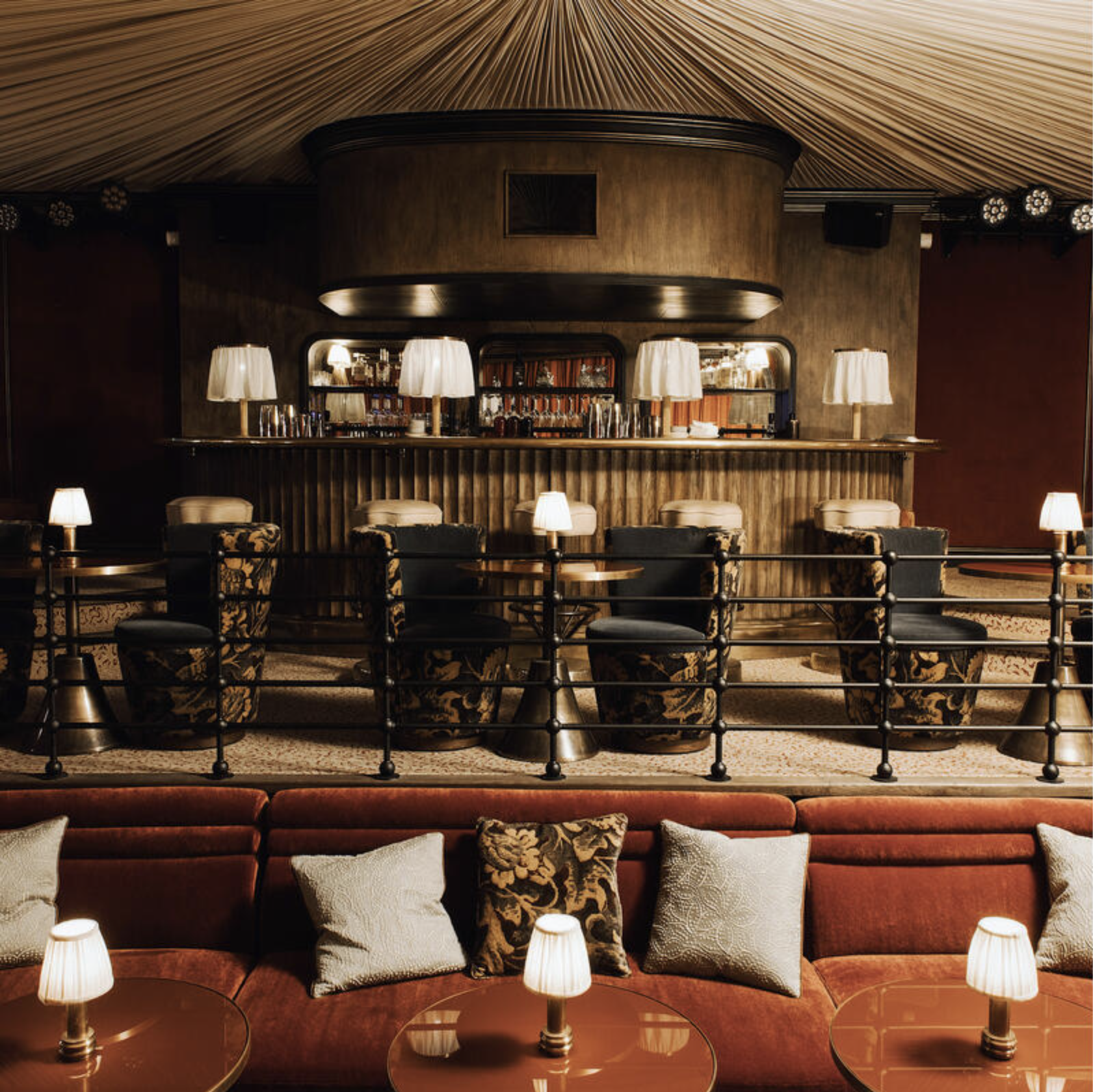 The Cabaret Room at Soho House Paris with dark velvet furniture, jazz club tables, gathered silk draping to canopy the ceiling and a fluted brass bar